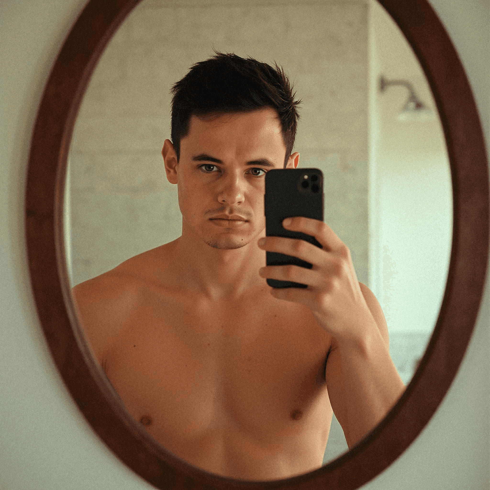Shirtless man taking mirror selfie